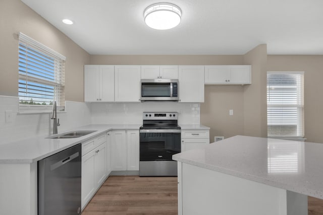 kitchen with white cabinetry, sink, tasteful backsplash, appliances with stainless steel finishes, and light wood-type flooring