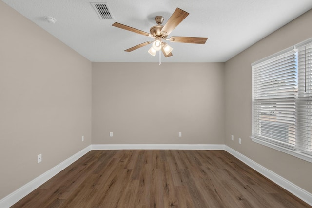 empty room featuring a textured ceiling, ceiling fan, and dark wood-type flooring