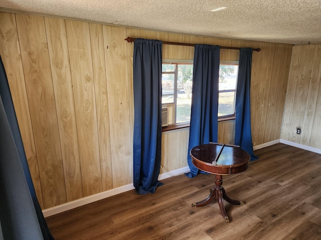 interior space featuring wooden walls, dark wood-type flooring, and a textured ceiling