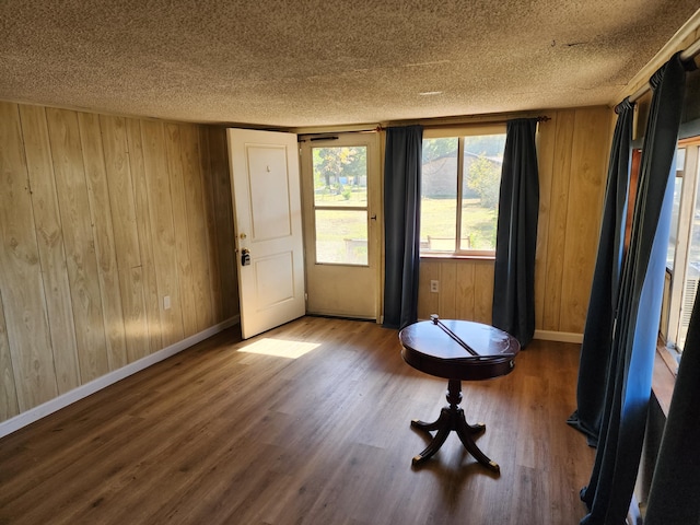 interior space with wooden walls, a textured ceiling, and hardwood / wood-style flooring