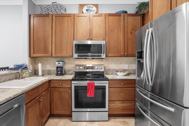 kitchen featuring decorative backsplash, appliances with stainless steel finishes, light stone countertops, sink, and light tile patterned flooring