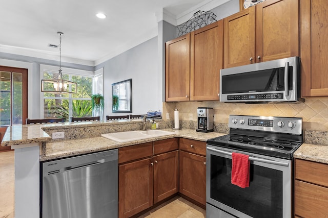 kitchen featuring kitchen peninsula, appliances with stainless steel finishes, light stone countertops, sink, and a notable chandelier