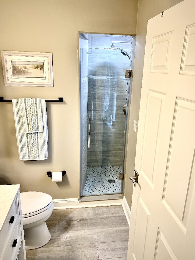 bathroom with hardwood / wood-style flooring, an enclosed shower, vanity, and toilet