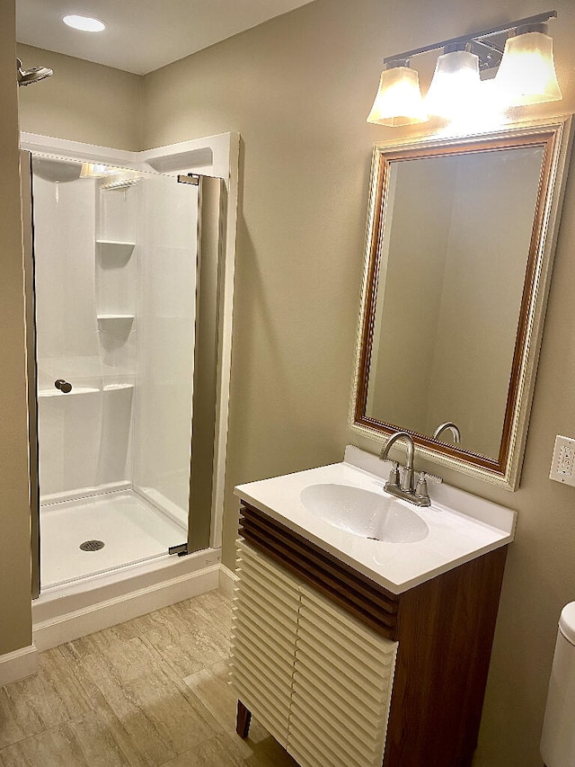 bathroom featuring toilet, a shower with shower door, and vanity