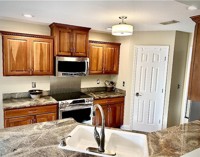 kitchen featuring appliances with stainless steel finishes, sink, and a textured ceiling