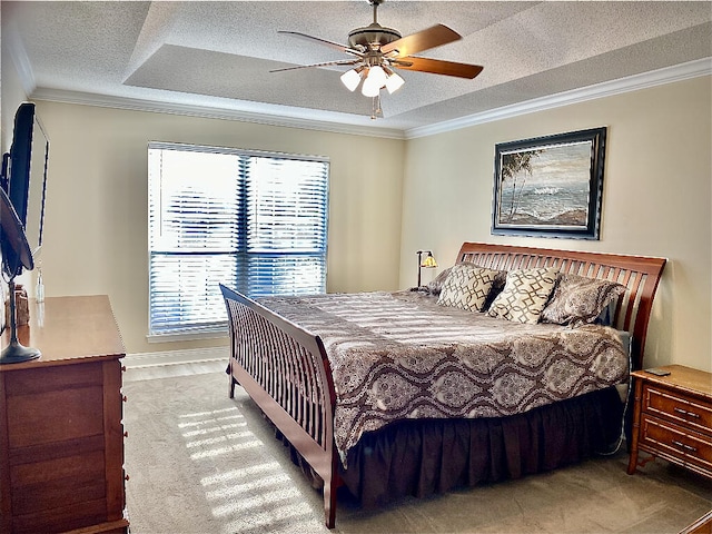 carpeted bedroom featuring a textured ceiling, ceiling fan, a tray ceiling, and multiple windows