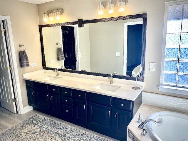 bathroom featuring vanity, hardwood / wood-style flooring, and tiled tub