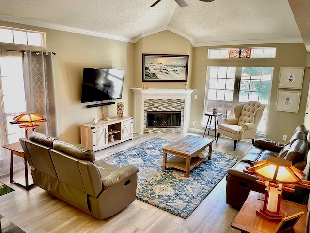 living room with light hardwood / wood-style floors, a textured ceiling, a stone fireplace, and vaulted ceiling