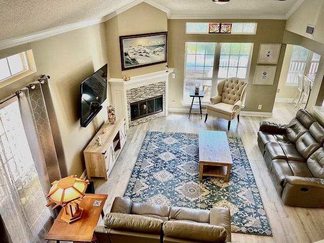 living room featuring a textured ceiling, light hardwood / wood-style flooring, ornamental molding, and a fireplace