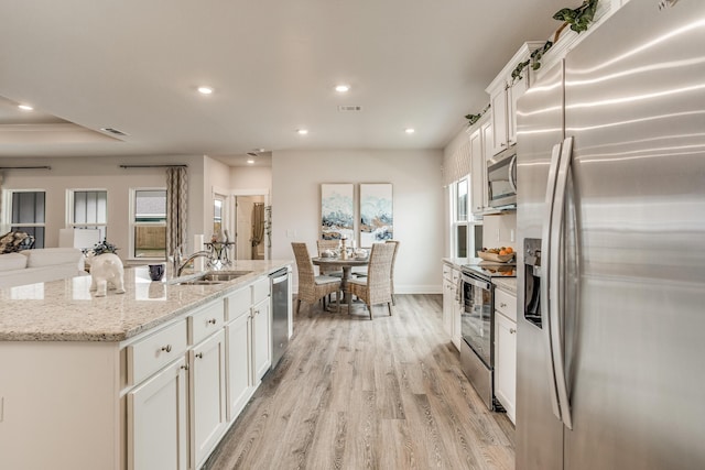 kitchen featuring white cabinets, light wood-type flooring, stainless steel appliances, and sink