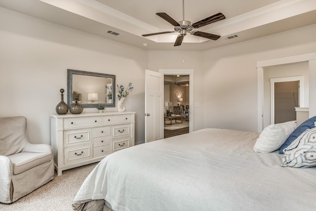 bedroom with a closet, a walk in closet, light colored carpet, and ceiling fan