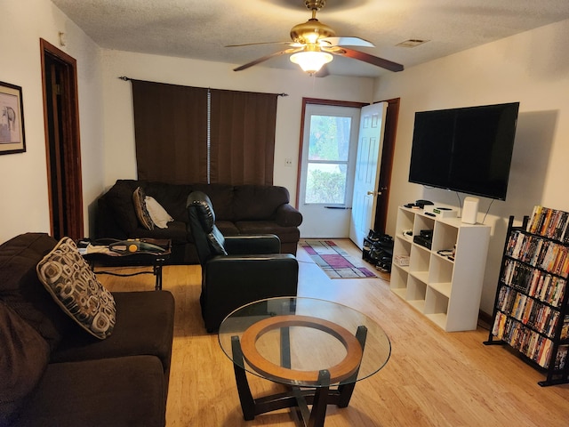 living room with ceiling fan, a textured ceiling, and light hardwood / wood-style flooring