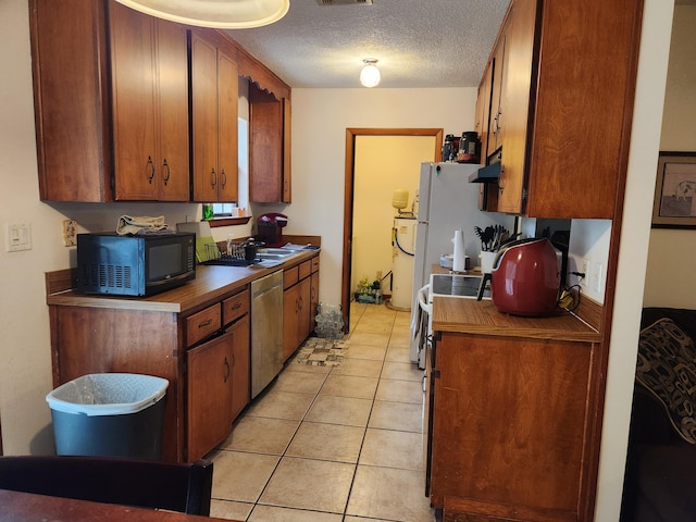 kitchen featuring stainless steel dishwasher, light tile patterned floors, a textured ceiling, and range