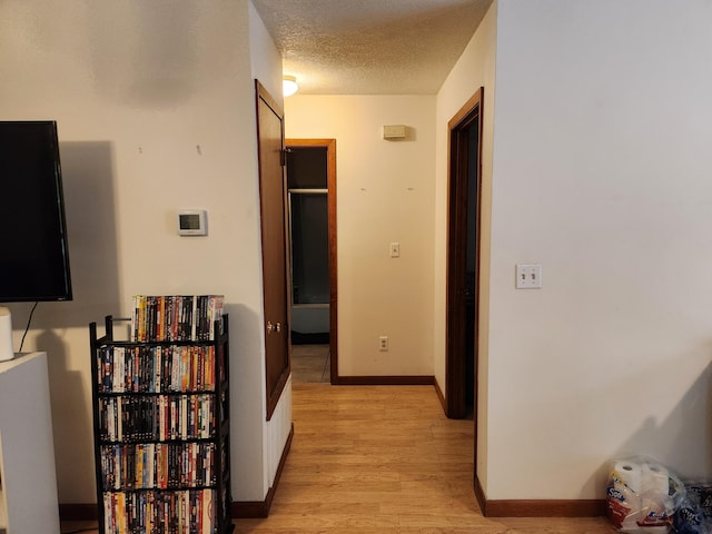 corridor with a textured ceiling and light wood-type flooring