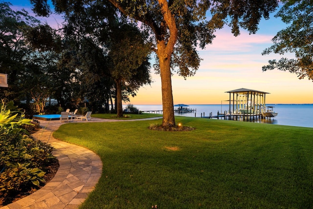 yard at dusk featuring a boat dock and a water view