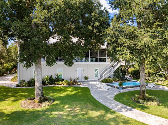 view of front of house featuring a patio area, a sunroom, and a front lawn