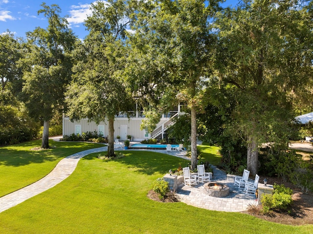 view of property's community with a patio, an outdoor fire pit, and a lawn