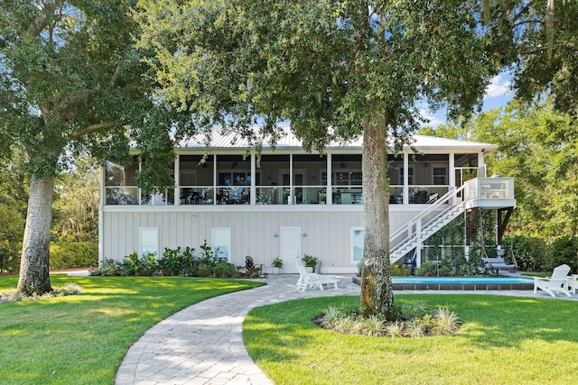 view of front facade with a sunroom, a front lawn, and a patio