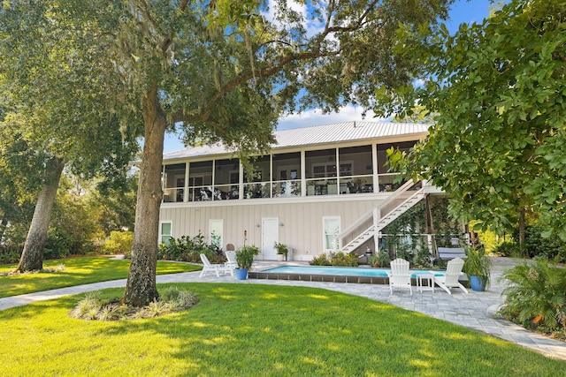 view of front of house featuring a front lawn, a patio area, and a sunroom