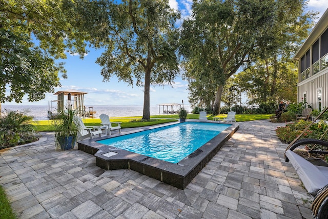 view of pool with a patio area, a water view, and a yard