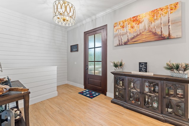 foyer featuring ornamental molding, wood-type flooring, and an inviting chandelier