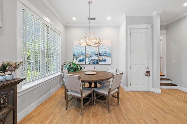 dining space with a chandelier, ornamental molding, and light wood-type flooring