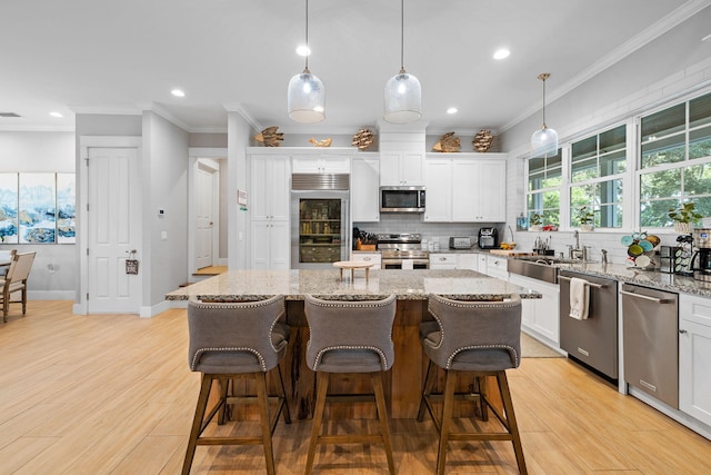 kitchen featuring appliances with stainless steel finishes, light hardwood / wood-style floors, a kitchen island, and white cabinetry