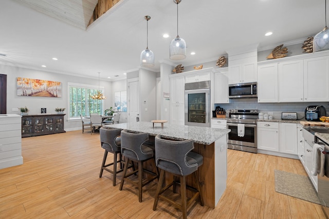 kitchen with stainless steel appliances, pendant lighting, light hardwood / wood-style flooring, a center island, and white cabinetry