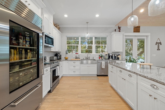 kitchen with sink, pendant lighting, decorative backsplash, white cabinets, and appliances with stainless steel finishes