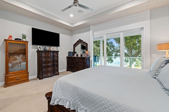 carpeted bedroom with a tray ceiling and ceiling fan