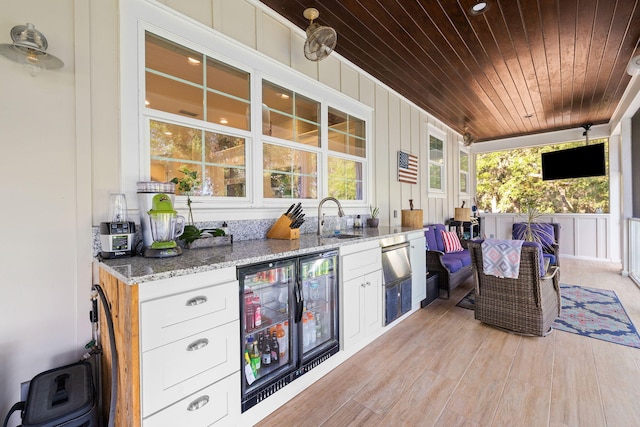 exterior space with a porch, wine cooler, exterior kitchen, and sink