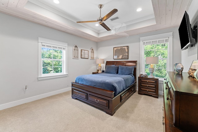 bedroom with a raised ceiling, multiple windows, and ceiling fan