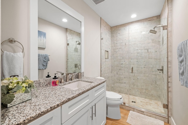 bathroom with hardwood / wood-style floors, vanity, a shower with shower door, and toilet