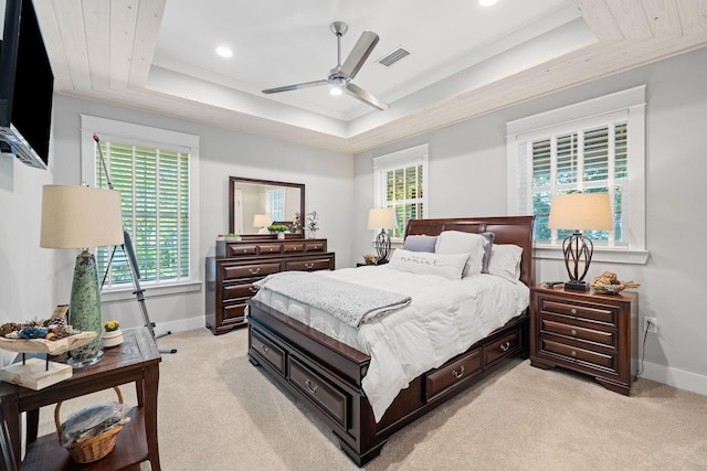 bedroom featuring a tray ceiling, multiple windows, light carpet, and ceiling fan