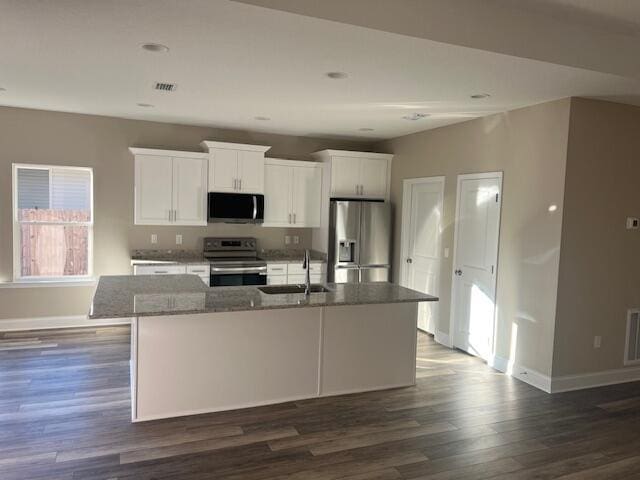 kitchen featuring sink, dark stone countertops, white cabinets, a kitchen island with sink, and stainless steel appliances