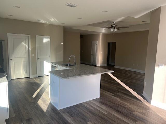 kitchen featuring light stone counters, sink, white cabinetry, and dark hardwood / wood-style flooring