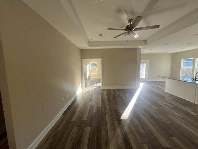 spare room featuring a raised ceiling, ceiling fan, and dark hardwood / wood-style flooring