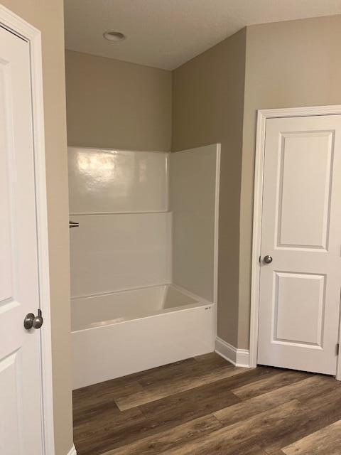 bathroom with hardwood / wood-style floors and washtub / shower combination