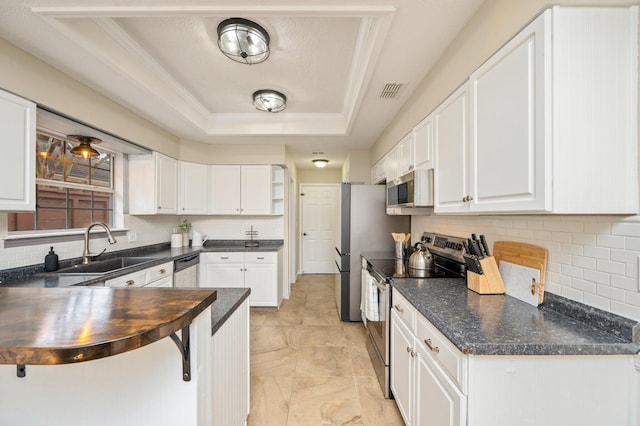 1905 W Mistral Ln, Fort Walton Beach, FL 32547 - kitchen with appliances with stainless steel finishes, a tray ceiling, white cabinets, decorative backsplash, and crown molding