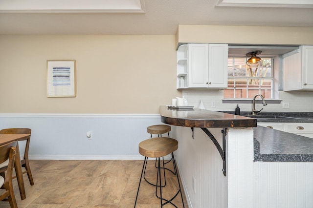 1905 W Mistral Ln, Fort Walton Beach, FL 32547 - kitchen with dark countertops, tasteful backsplash, a breakfast bar, and white cabinets