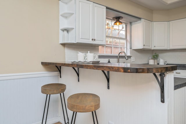 1905 W Mistral Ln, Fort Walton Beach, FL 32547 - kitchen featuring white cabinetry, a kitchen breakfast bar, backsplash, a wainscoted wall, and open shelves