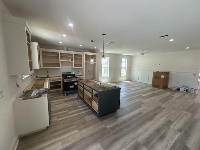 kitchen featuring stainless steel gas range, recessed lighting, ceiling fan, and wood finished floors