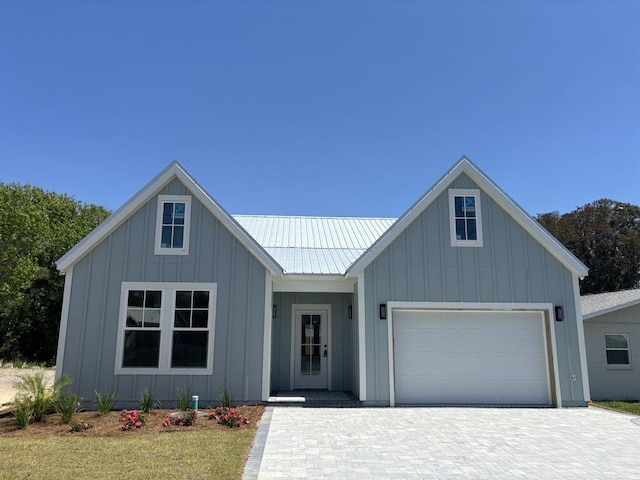 view of front of home featuring board and batten siding, decorative driveway, metal roof, and a garage