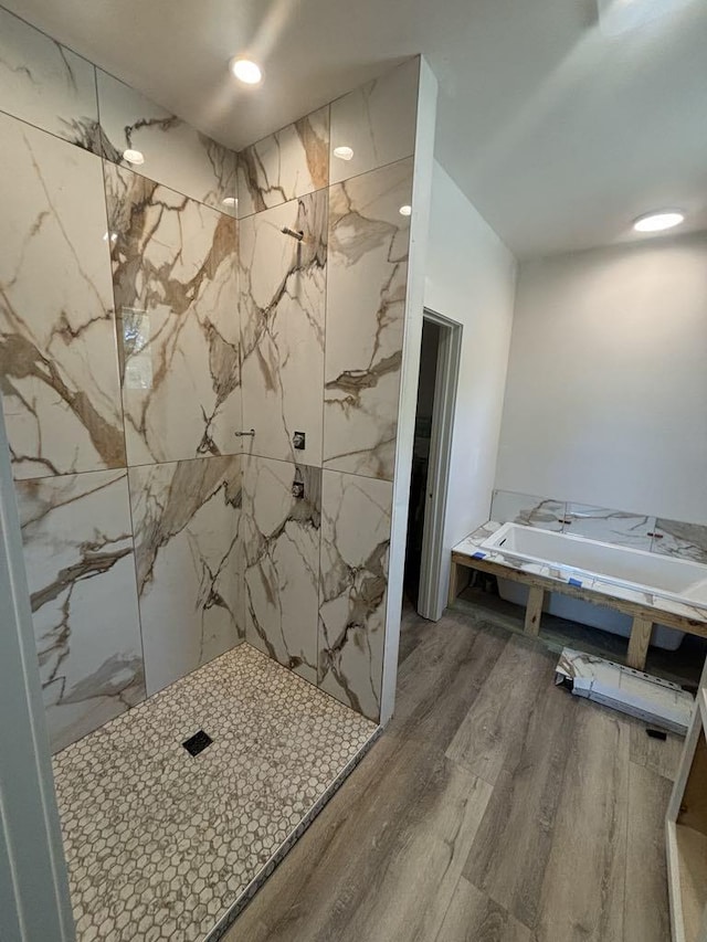 bathroom with a marble finish shower and wood finished floors