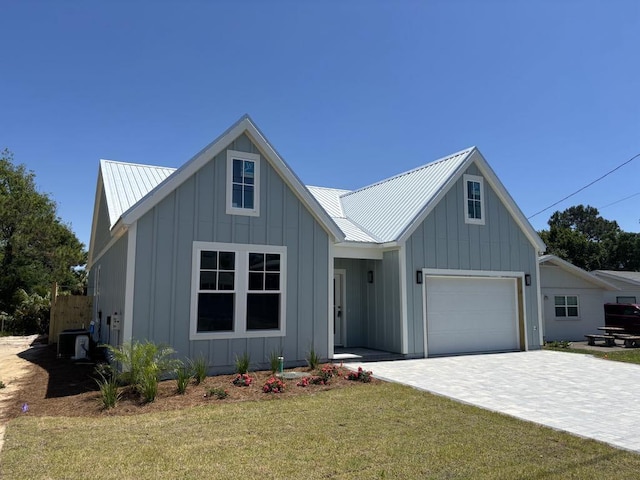 view of front facade featuring board and batten siding, decorative driveway, metal roof, and a front lawn