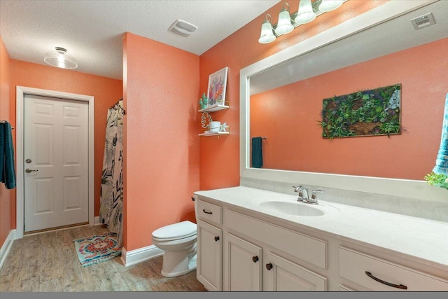 bathroom with vanity, a textured ceiling, wood-type flooring, toilet, and curtained shower