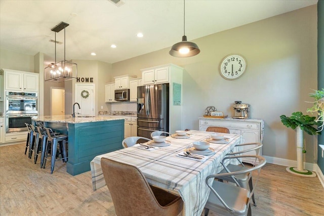 dining space with light hardwood / wood-style floors, an inviting chandelier, and sink