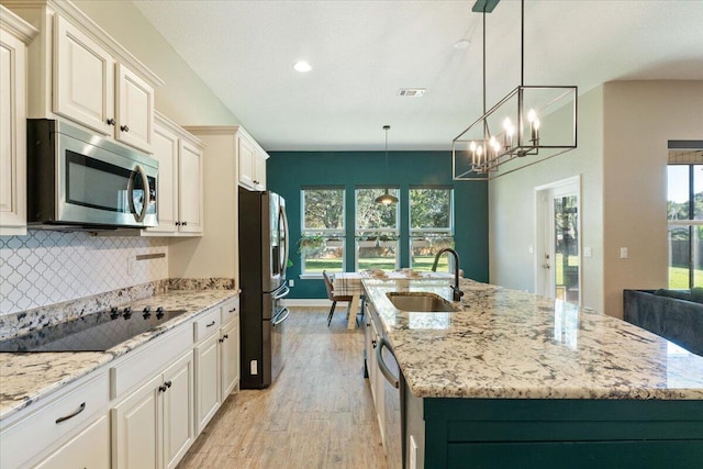 kitchen with a center island with sink, light hardwood / wood-style floors, sink, and appliances with stainless steel finishes