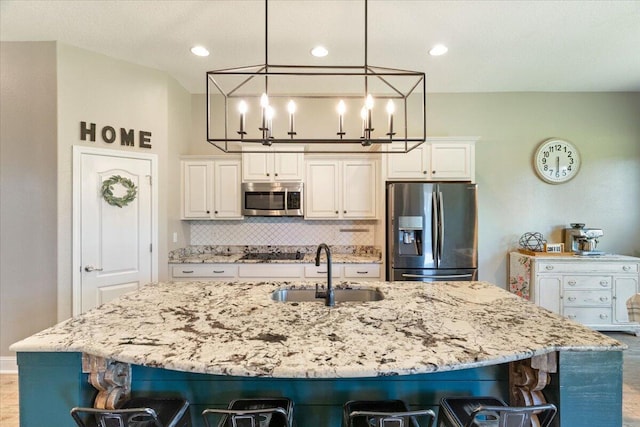 kitchen with white cabinets, a kitchen bar, sink, and appliances with stainless steel finishes