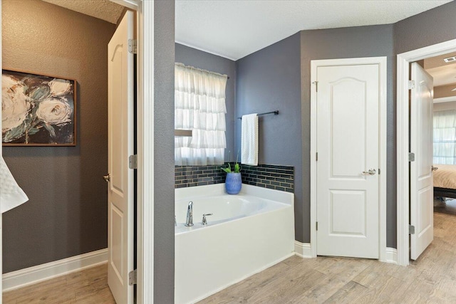 bathroom with hardwood / wood-style flooring, a wealth of natural light, and a tub